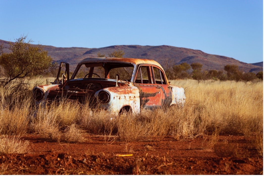 Old rusted car in field